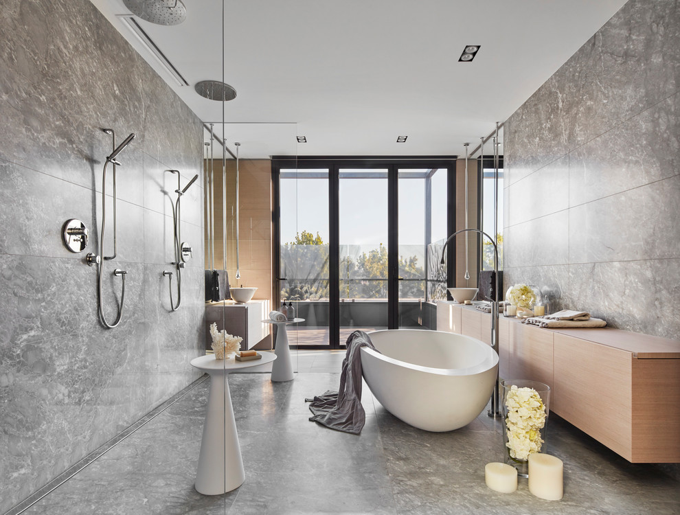 Photo of a contemporary master bathroom in Melbourne with flat-panel cabinets, light wood cabinets, a freestanding tub, a double shower, gray tile, grey walls, a vessel sink, wood benchtops, grey floor, an open shower and beige benchtops.