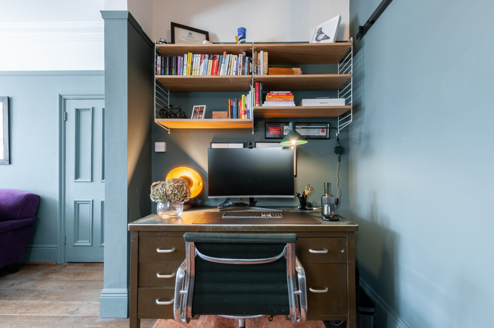 Inspiration for a large eclectic home office in Kent with green walls, medium hardwood flooring, a standard fireplace, a stone fireplace surround and brown floors.