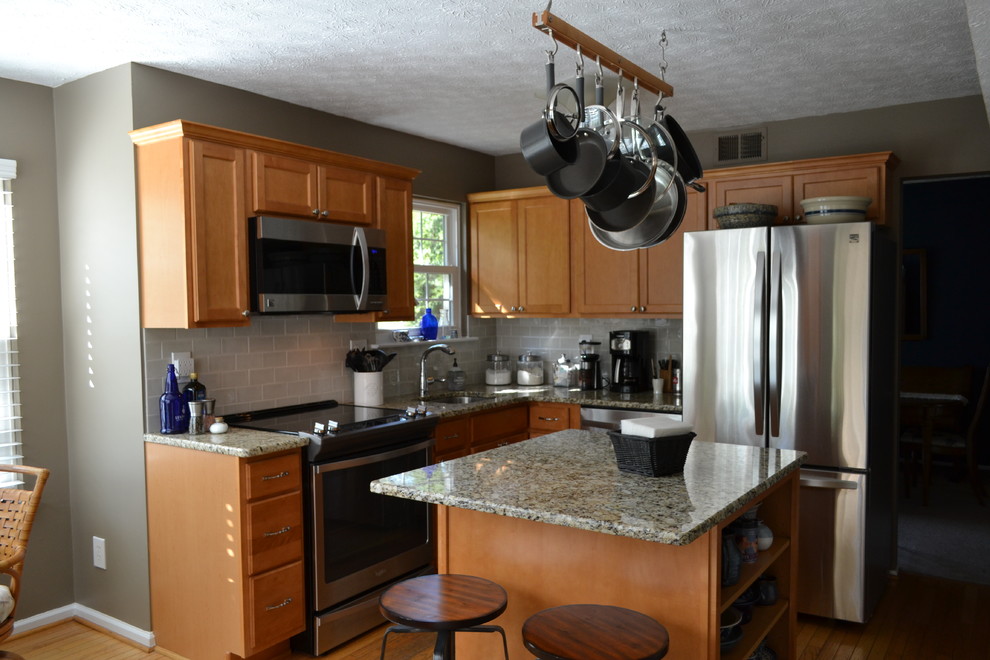 Example of a transitional u-shaped medium tone wood floor eat-in kitchen design in Baltimore with an undermount sink, flat-panel cabinets, medium tone wood cabinets, granite countertops, gray backsplash, porcelain backsplash, stainless steel appliances and an island