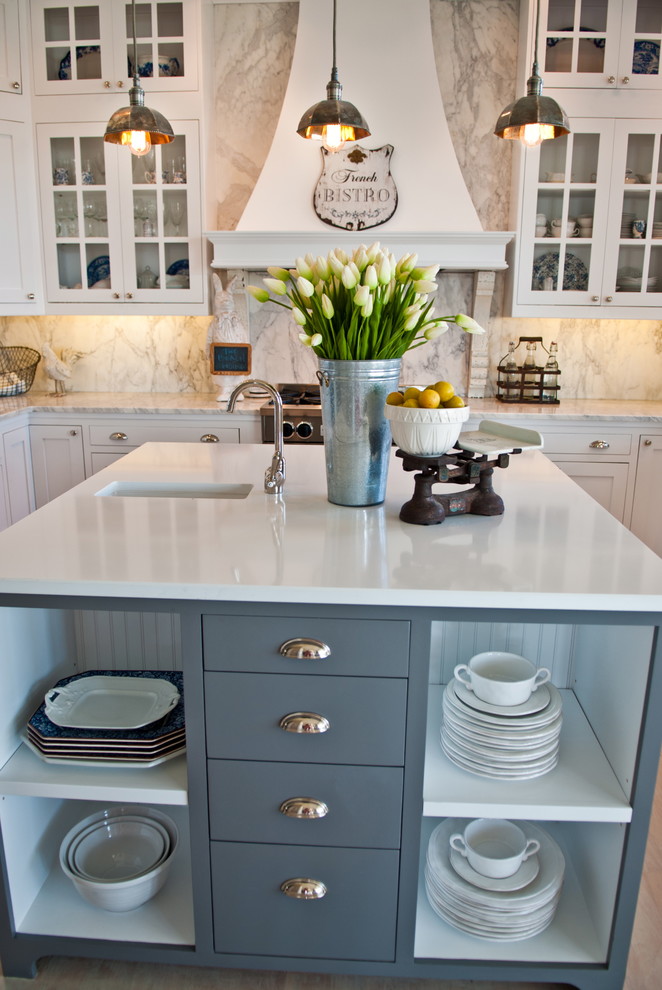 This is an example of a beach style kitchen in Seattle with glass-front cabinets, blue cabinets, quartz benchtops, white splashback and marble splashback.