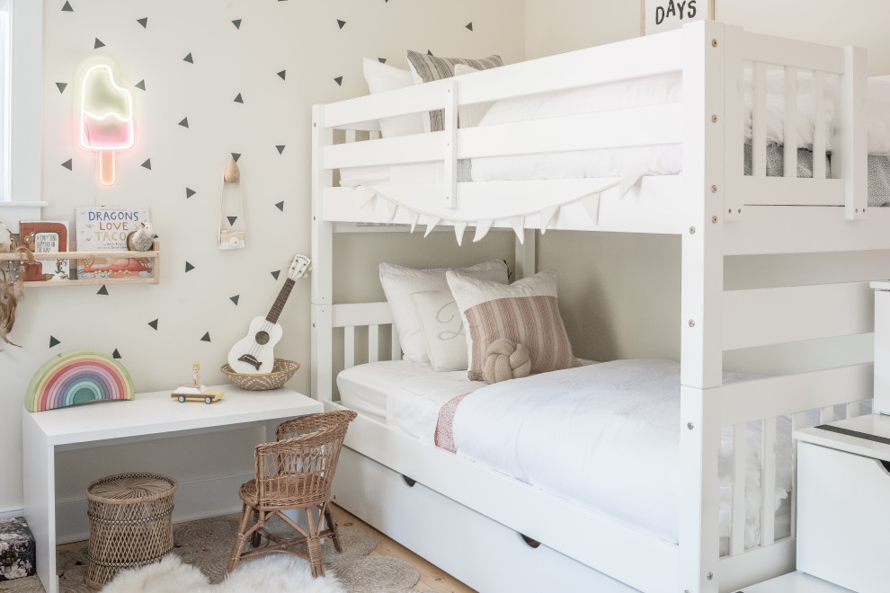Design ideas for a beach style gender-neutral kids' bedroom for kids 4-10 years old in New York with multi-coloured walls and light hardwood floors.
