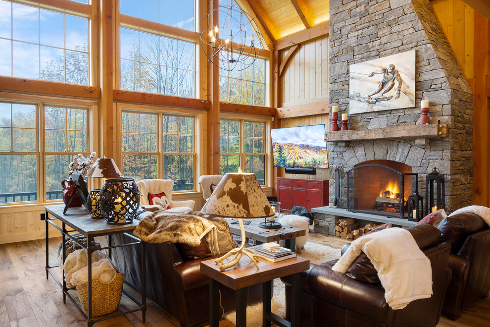 Design ideas for a large country open concept family room in Boston with medium hardwood floors, a standard fireplace, a stone fireplace surround, a wall-mounted tv, beige walls and brown floor.