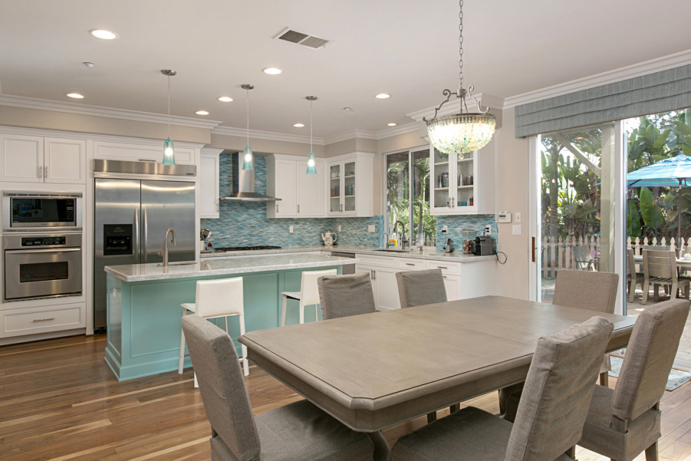 Photo of a medium sized contemporary l-shaped open plan kitchen in San Diego with a submerged sink, beaded cabinets, turquoise cabinets, quartz worktops, blue splashback, glass tiled splashback, stainless steel appliances, light hardwood flooring, an island, beige floors and white worktops.