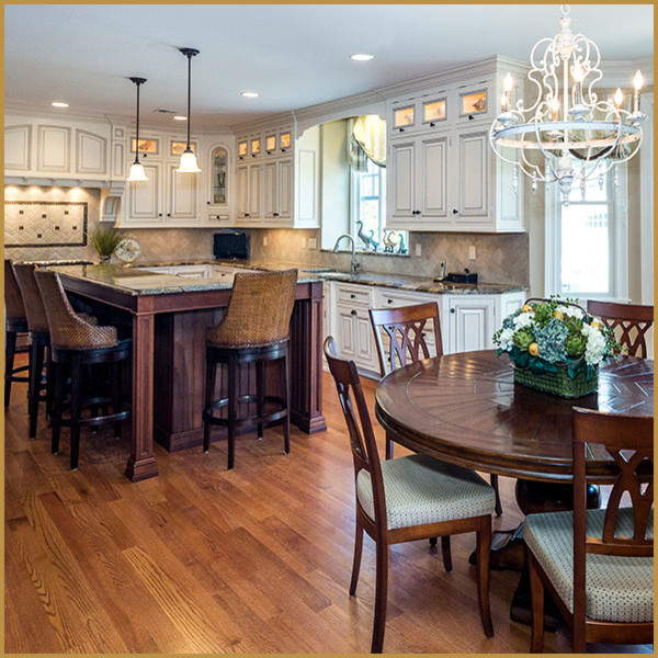 Design ideas for a large traditional l-shaped eat-in kitchen in New York with an undermount sink, raised-panel cabinets, white cabinets, granite benchtops, beige splashback, travertine splashback, stainless steel appliances, medium hardwood floors, with island and brown floor.