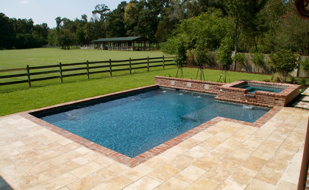 This is an example of a mid-sized traditional backyard rectangular lap pool in New Orleans with a hot tub and brick pavers.