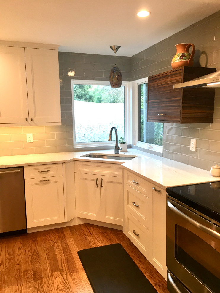 Inspiration for a small transitional u-shaped separate kitchen in Denver with a drop-in sink, shaker cabinets, white cabinets, quartz benchtops, grey splashback, subway tile splashback, stainless steel appliances, medium hardwood floors, a peninsula, brown floor and white benchtop.