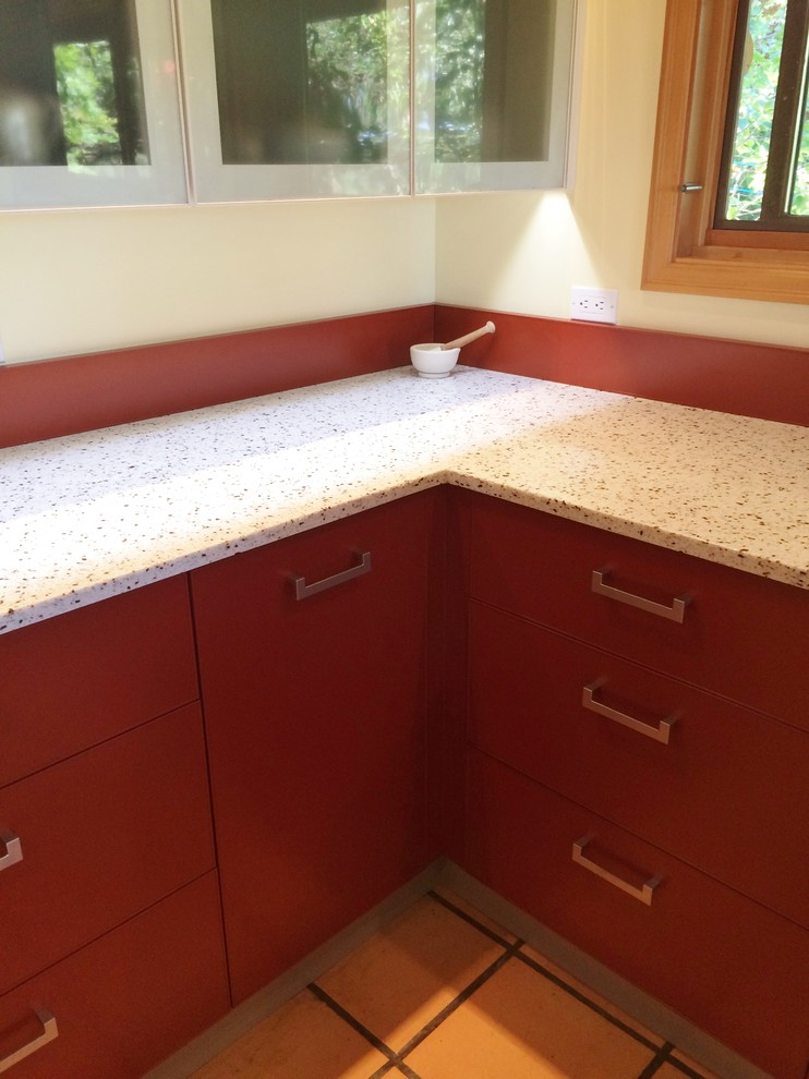 Inspiration for a large contemporary u-shaped kitchen in Vancouver with an undermount sink, flat-panel cabinets, red cabinets, recycled glass benchtops, red splashback and terra-cotta floors.