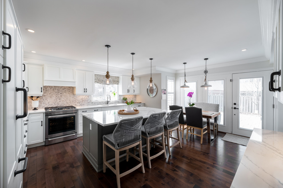 Example of a transitional dark wood floor and brown floor kitchen design in Toronto with white cabinets, paneled appliances, an island and white countertops