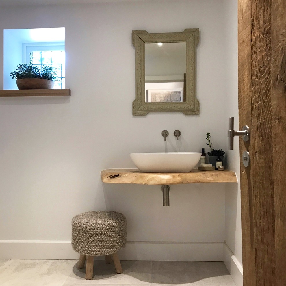 Design ideas for a small contemporary powder room in Cheshire with a wall-mount toilet, white tile, white walls, ceramic floors, a trough sink, wood benchtops and white floor.