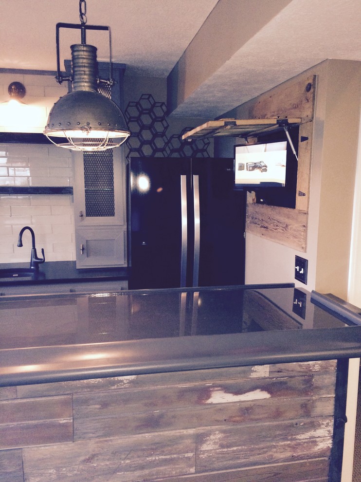 Photo of a small industrial galley seated home bar in Columbus with an undermount sink, glass-front cabinets, grey cabinets, white splashback, subway tile splashback, slate floors and black floor.