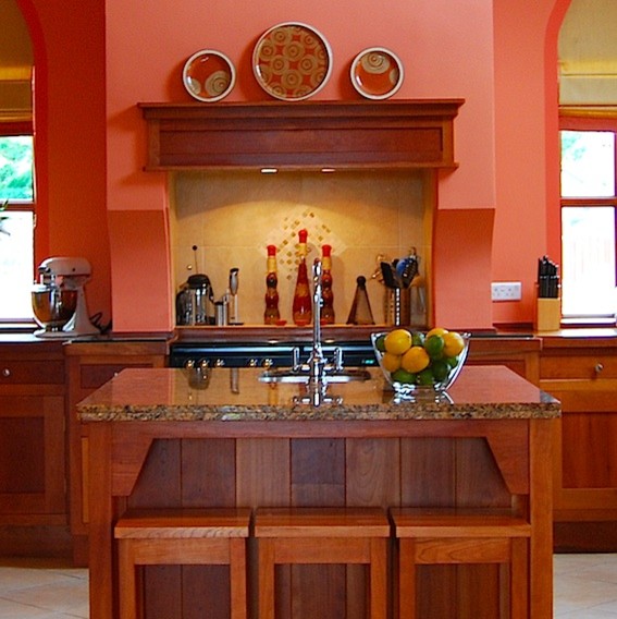 Photo of a traditional u-shaped eat-in kitchen in Other with a drop-in sink, shaker cabinets, medium wood cabinets, wood benchtops, beige splashback, stone tile splashback and panelled appliances.