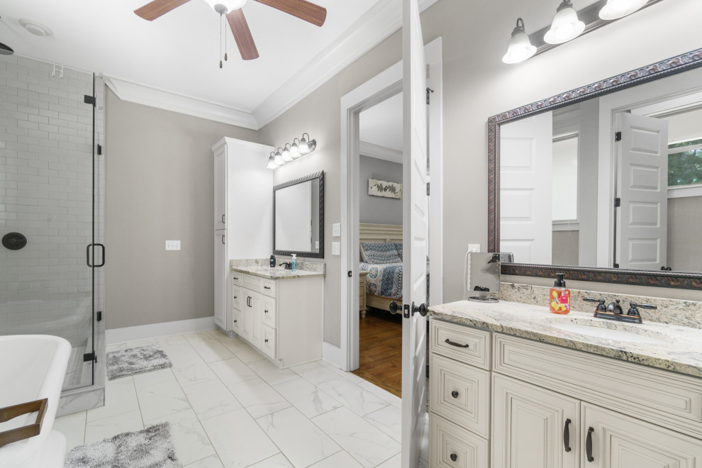 This is an example of a large rural ensuite bathroom in Atlanta with beaded cabinets, beige cabinets, a freestanding bath, an alcove shower, a one-piece toilet, grey tiles, mosaic tiles, grey walls, marble flooring, a built-in sink, granite worktops, white floors, a hinged door, beige worktops, double sinks and a built in vanity unit.