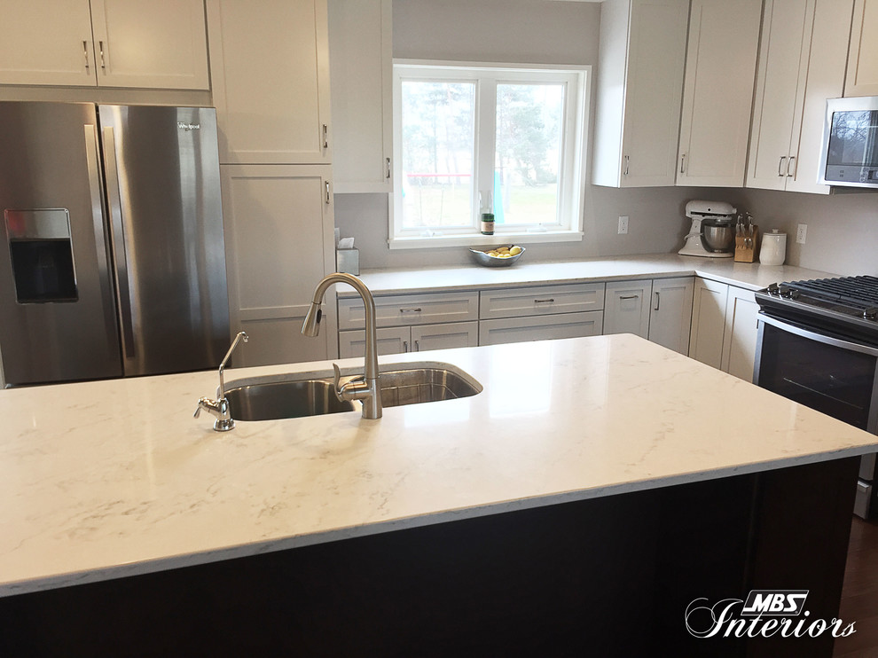 Inspiration for a mid-sized transitional l-shaped eat-in kitchen in Cleveland with an undermount sink, shaker cabinets, white cabinets, quartz benchtops, stainless steel appliances, medium hardwood floors and with island.