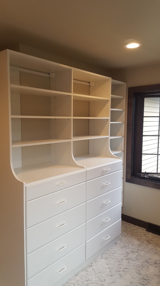 This is an example of a mid-sized traditional gender-neutral walk-in wardrobe in Other with open cabinets, white cabinets, ceramic floors and white floor.