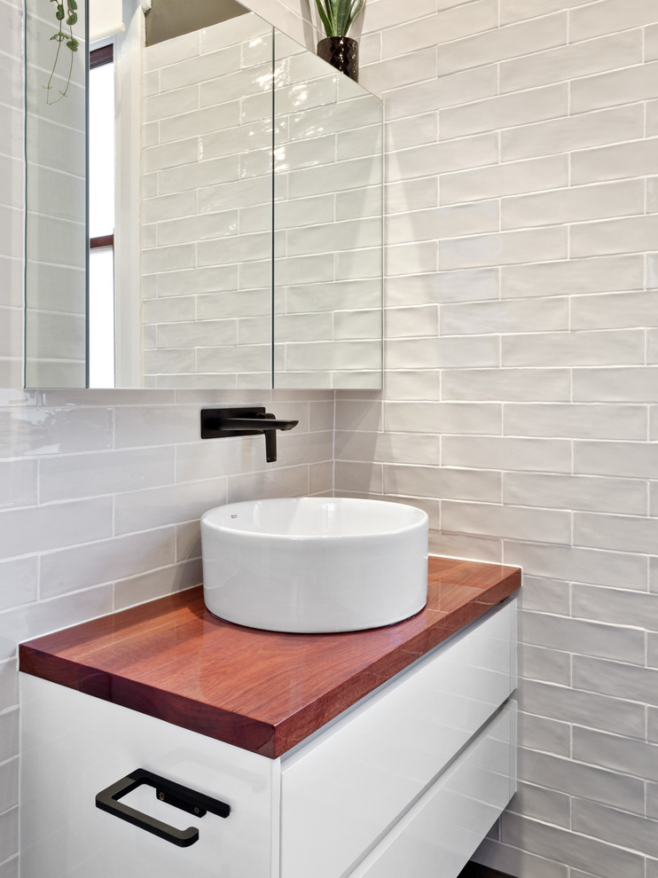 Mid-sized contemporary master bathroom in Perth with a one-piece toilet, black and white tile, subway tile, ceramic floors, a vessel sink, wood benchtops, an open shower, white walls and black floor.