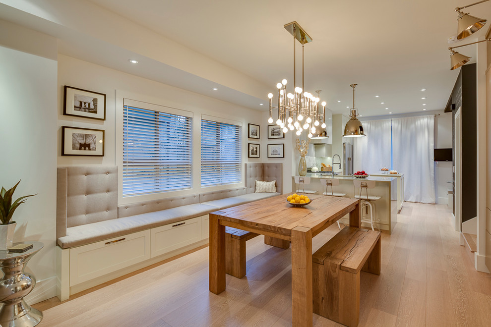 This is an example of a transitional open plan dining in Vancouver with white walls and medium hardwood floors.