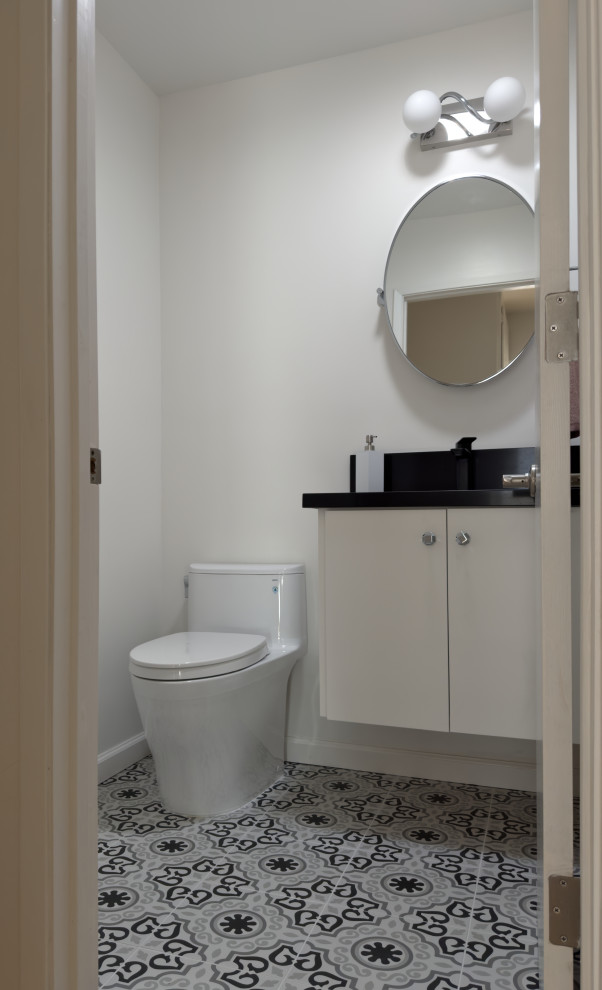 Aménagement d'un WC et toilettes contemporain avec un placard à porte plane, des portes de placard blanches, carreaux de ciment au sol, un plan de toilette en granite, un sol multicolore, un plan de toilette noir et meuble-lavabo suspendu.