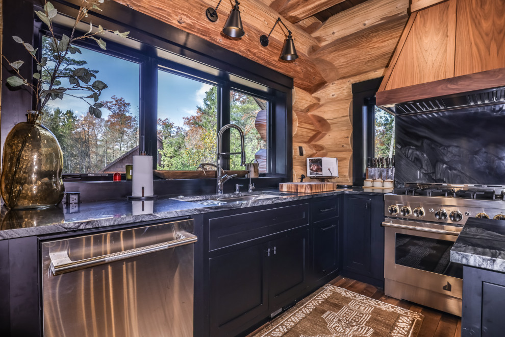 Open concept kitchen - rustic u-shaped dark wood floor, brown floor and exposed beam open concept kitchen idea with an undermount sink, shaker cabinets, black cabinets, solid surface countertops, multicolored backsplash, stainless steel appliances, an island and multicolored countertops