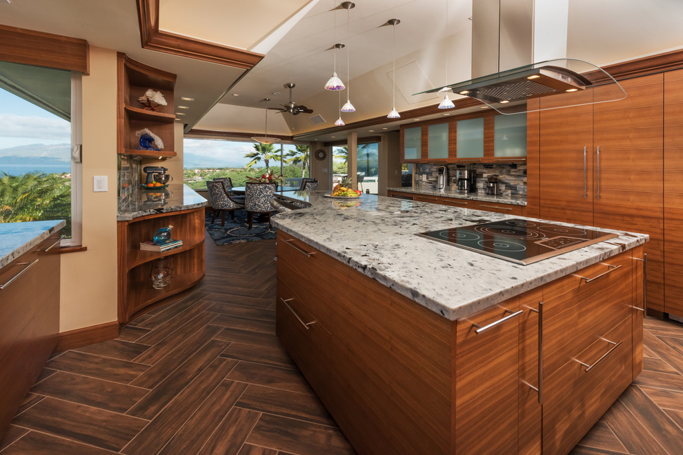 Contemporary u-shaped kitchen in Hawaii with a single-bowl sink, flat-panel cabinets, medium wood cabinets, granite benchtops, blue splashback, glass tile splashback, panelled appliances, porcelain floors, with island, brown floor and white benchtop.