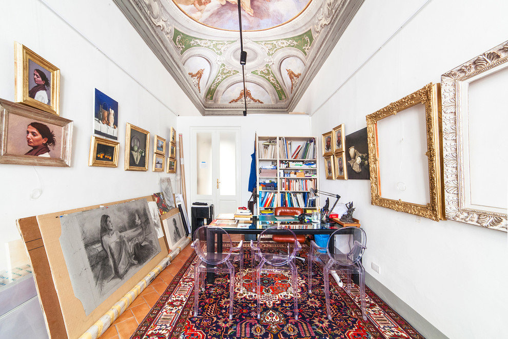 Photo of a large eclectic craft room in Florence with white walls, terra-cotta floors, no fireplace, a freestanding desk and red floor.