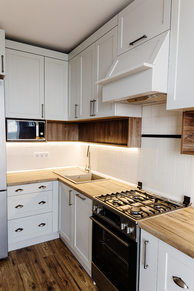 Inspiration for a mid-sized transitional u-shaped dark wood floor and brown floor eat-in kitchen remodel in DC Metro with a drop-in sink, recessed-panel cabinets, white cabinets, wood countertops, white backsplash, ceramic backsplash, stainless steel appliances, a peninsula and brown countertops
