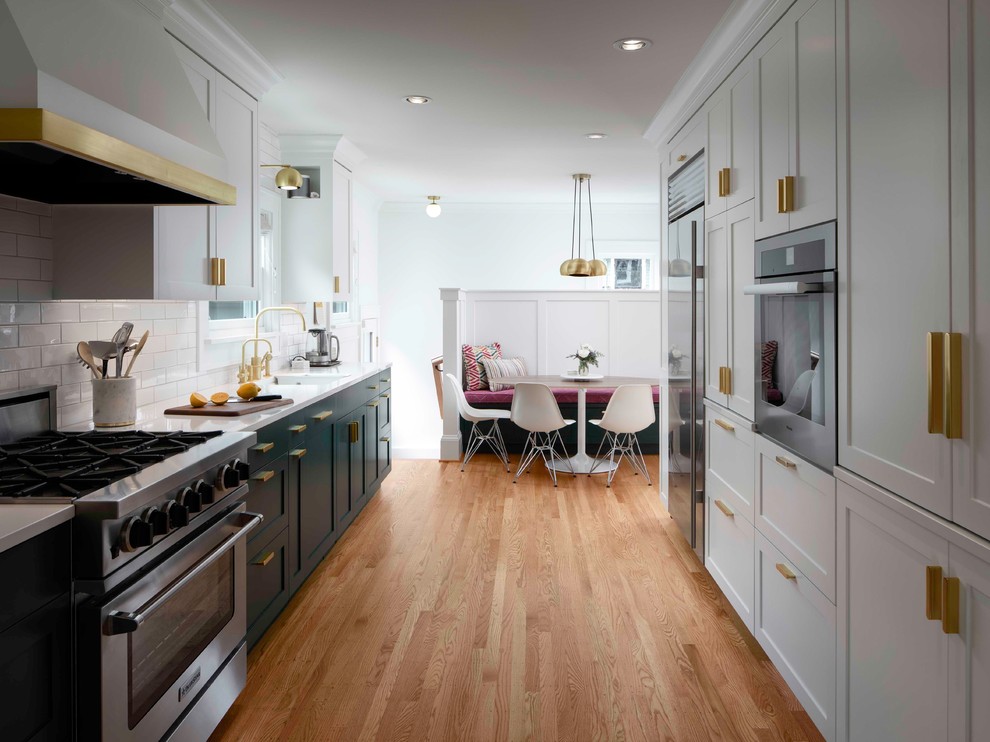 Eat-in kitchen - transitional galley medium tone wood floor and brown floor eat-in kitchen idea in Portland with shaker cabinets, white cabinets, white backsplash, subway tile backsplash, stainless steel appliances, no island and white countertops
