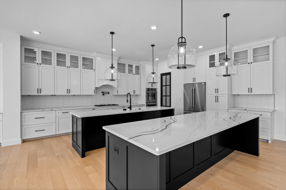 Eat-in kitchen - large transitional eat-in kitchen idea in Cincinnati with a single-bowl sink, shaker cabinets, white cabinets, quartzite countertops, white backsplash, ceramic backsplash, stainless steel appliances, two islands and white countertops