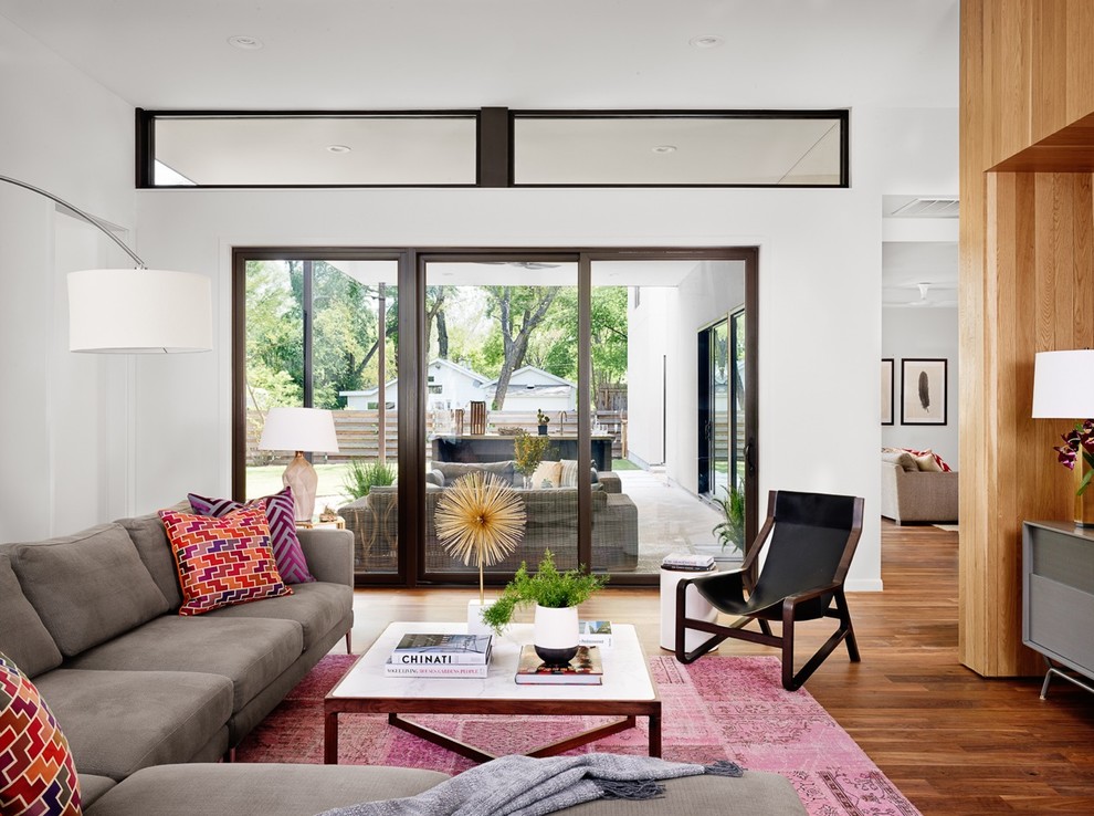 Midcentury open concept living room in Austin with white walls and medium hardwood floors.