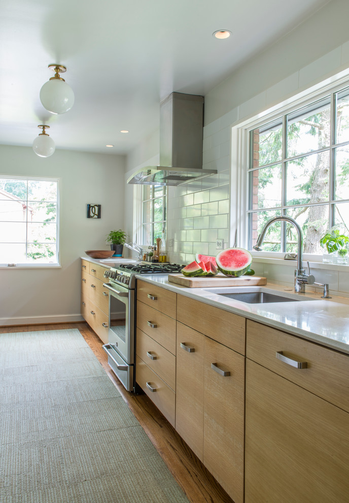Enclosed kitchen - mid-sized transitional galley medium tone wood floor enclosed kitchen idea in DC Metro with an undermount sink, flat-panel cabinets, light wood cabinets, quartz countertops, white backsplash, ceramic backsplash, stainless steel appliances and no island