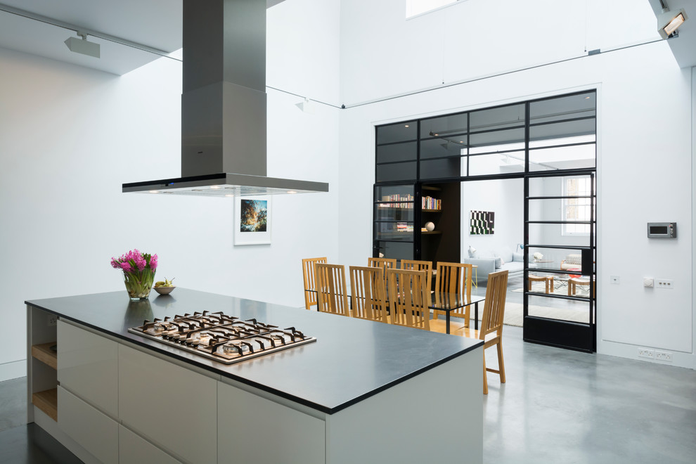 Inspiration for an expansive industrial single-wall eat-in kitchen in London with flat-panel cabinets, solid surface benchtops, concrete floors, with island and stainless steel appliances.