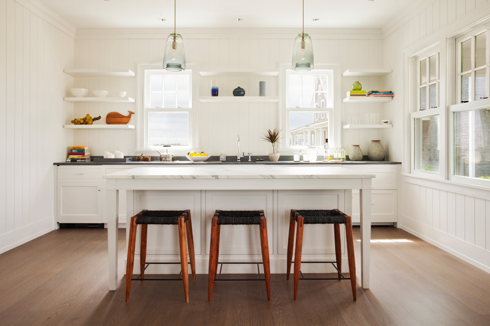 Photo of a beach style galley kitchen in Boston with an undermount sink, open cabinets, white cabinets, dark hardwood floors, with island and brown floor.