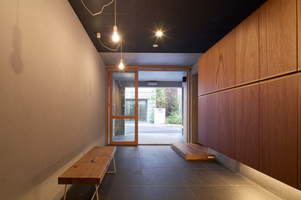 Immagine di un ingresso moderno di medie dimensioni con pareti grigie, pavimento con piastrelle in ceramica, una porta scorrevole e pavimento nero