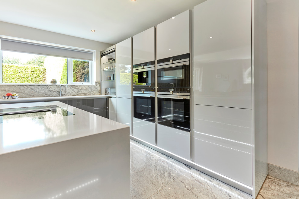 Inspiration for a mid-sized contemporary u-shaped eat-in kitchen in Other with an integrated sink, flat-panel cabinets, white cabinets, quartzite benchtops, grey splashback, stone slab splashback, black appliances, marble floors, with island, grey floor, white benchtop and coffered.