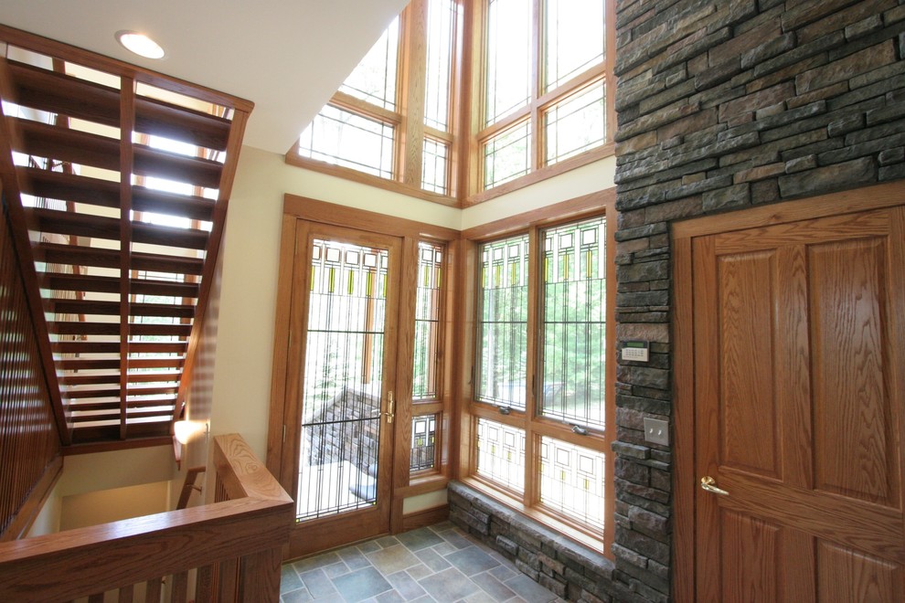 This is an example of a mid-sized arts and crafts foyer in Cincinnati with multi-coloured walls, slate floors, a single front door and a medium wood front door.