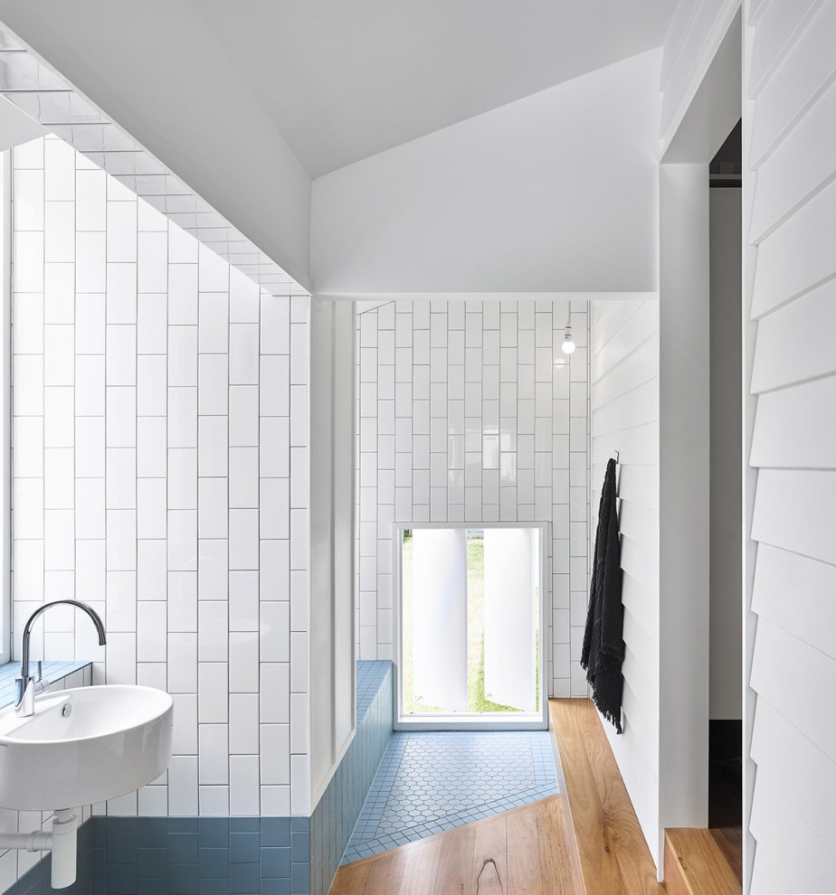 Beach style bathroom in Brisbane with blue tile, white tile, subway tile, white walls, a wall-mount sink and vaulted.