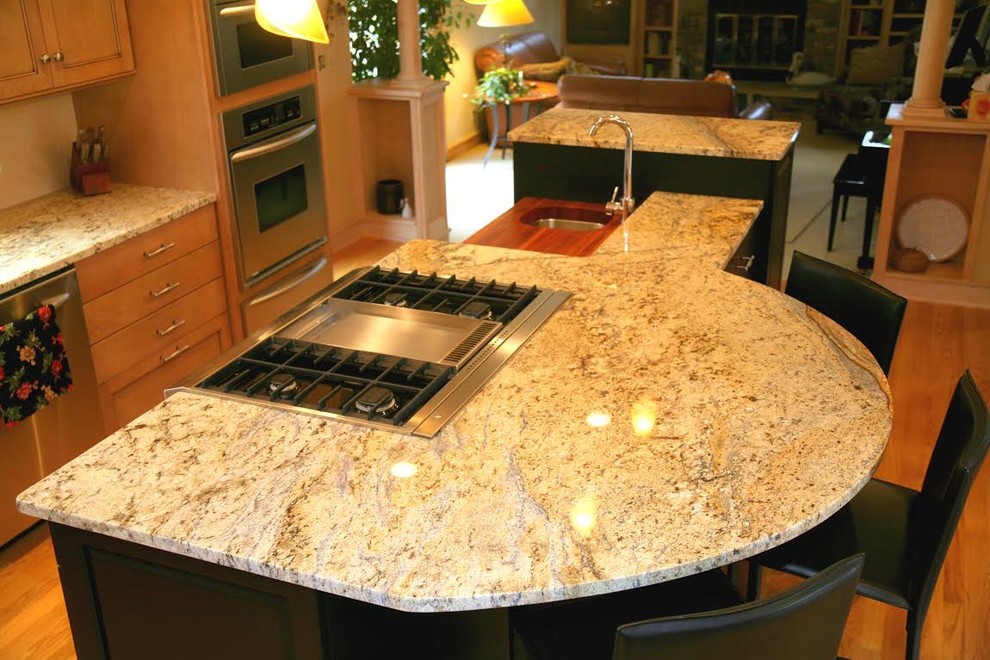 Example of a mid-sized transitional l-shaped light wood floor and beige floor enclosed kitchen design in Milwaukee with recessed-panel cabinets, light wood cabinets, granite countertops, stainless steel appliances, an island and an undermount sink