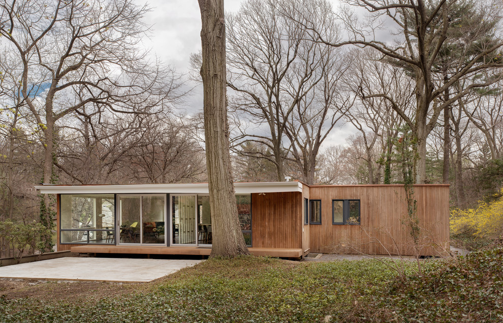 Large midcentury two-storey exterior in New York with wood siding and a flat roof.