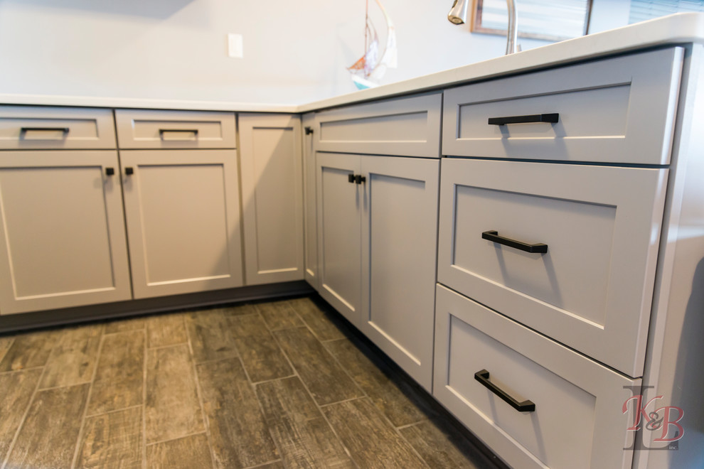 Inspiration for a mid-sized transitional porcelain tile and brown floor eat-in kitchen remodel with an undermount sink, recessed-panel cabinets, white cabinets, quartz countertops, gray backsplash, subway tile backsplash, stainless steel appliances, an island and white countertops