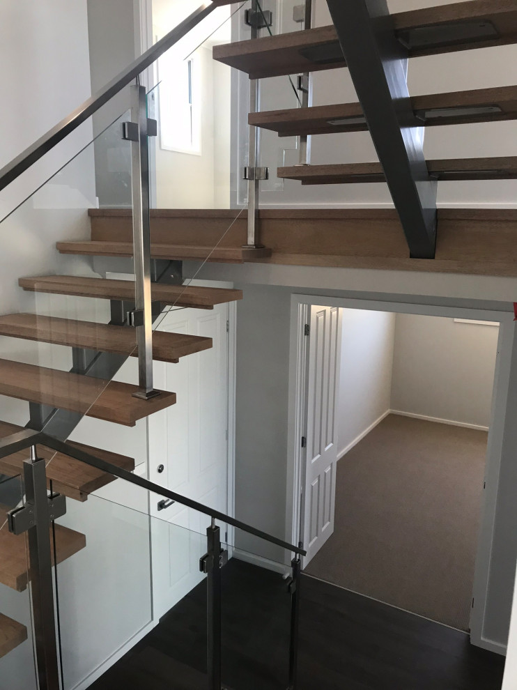 Large beach style wood straight staircase in Central Coast with metal risers and glass railing.