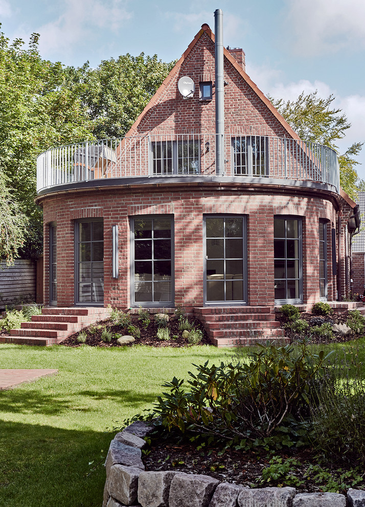 Inspiration for a mid-sized scandinavian two-storey brick red exterior in Other with a gable roof.