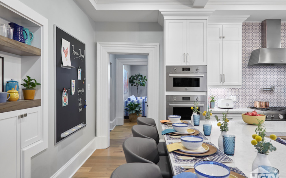 Landhaus Wohnküche in U-Form mit weißen Schränken, Küchenrückwand in Blau, Küchengeräten aus Edelstahl, hellem Holzboden, Kücheninsel, braunem Boden und weißer Arbeitsplatte in Toronto