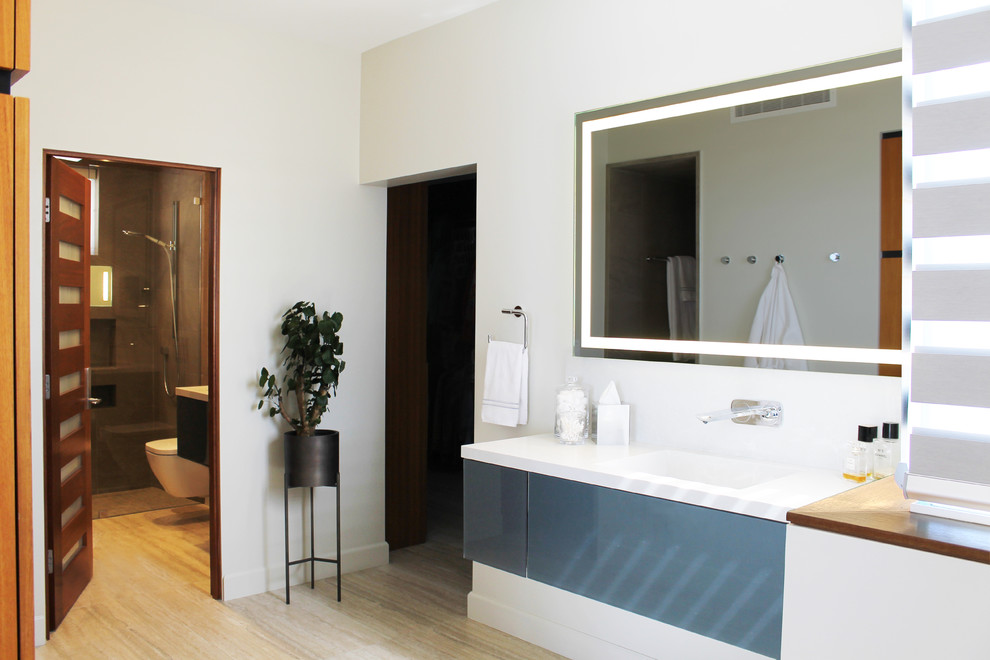 Photo of a mid-sized modern master bathroom in Los Angeles with glass-front cabinets, blue cabinets, a curbless shower, a wall-mount toilet, cement tile, white walls, travertine floors, an undermount sink, quartzite benchtops, beige floor, a hinged shower door, white benchtops, a single vanity and a floating vanity.