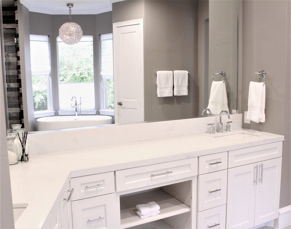 Design ideas for a large modern master bathroom in Houston with recessed-panel cabinets, white cabinets, a freestanding tub, a curbless shower, a one-piece toilet, gray tile, ceramic tile, grey walls, an undermount sink, engineered quartz benchtops, a hinged shower door and white benchtops.
