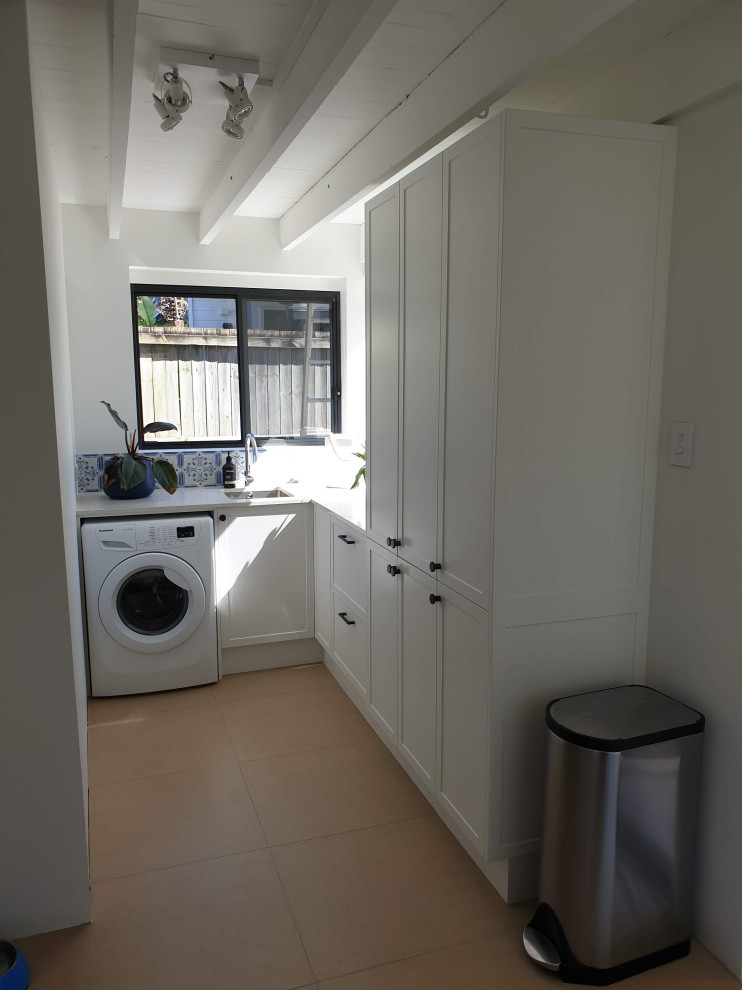 Small traditional laundry room in Brisbane with white walls, an integrated washer and dryer and beige floor.