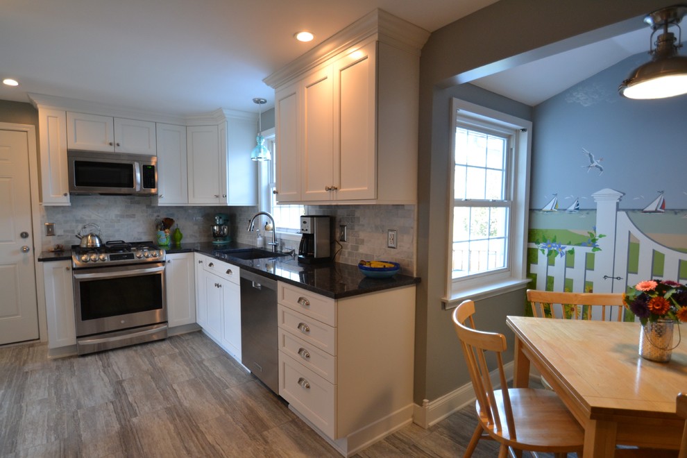 Photo of a beach style u-shaped separate kitchen in Charlotte with white cabinets, grey splashback, stainless steel appliances, no island, grey floor, a double-bowl sink, shaker cabinets, granite benchtops, marble splashback and vinyl floors.