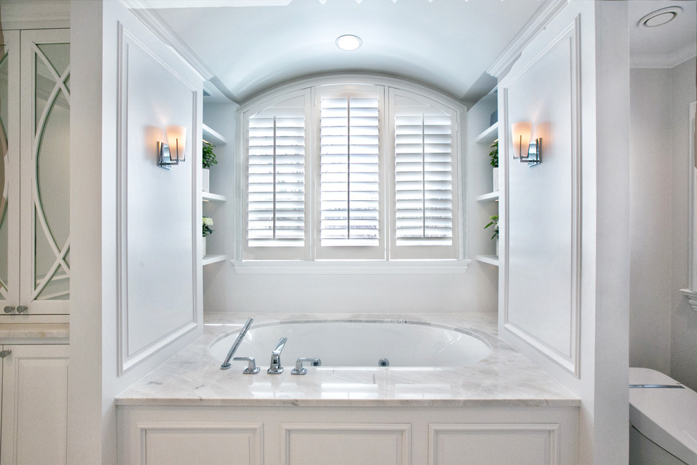 Inspiration for a mid-sized traditional master wet room bathroom in Chicago with raised-panel cabinets, white cabinets, an undermount tub, a one-piece toilet, white tile, marble, grey walls, marble floors, an undermount sink, marble benchtops, white floor, a hinged shower door and white benchtops.