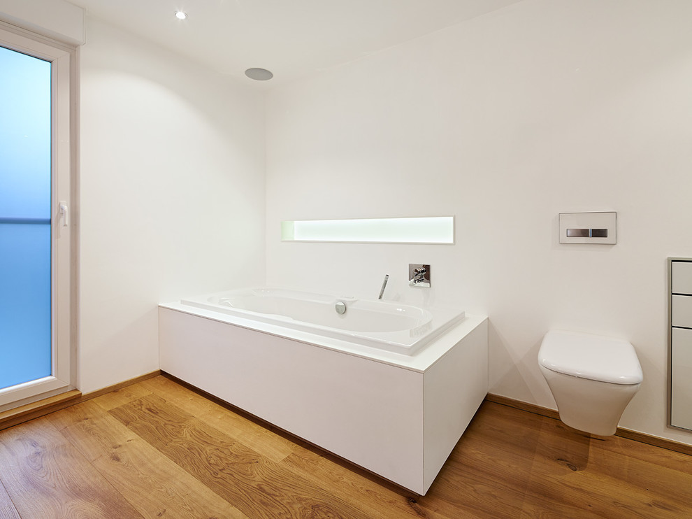 Design ideas for a large contemporary 3/4 bathroom in Dusseldorf with flat-panel cabinets, brown cabinets, a drop-in tub, an open shower, a wall-mount toilet, white walls, medium hardwood floors, wood benchtops and a drop-in sink.