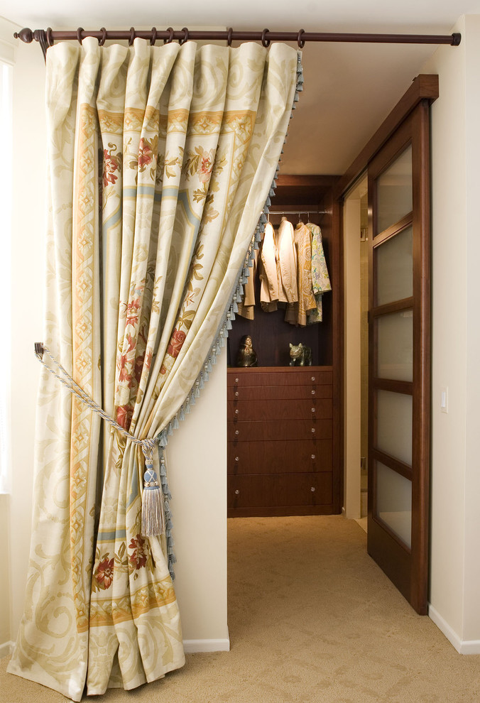 Inspiration for a mid-sized traditional gender-neutral walk-in wardrobe in Chicago with flat-panel cabinets, dark wood cabinets, carpet and beige floor.