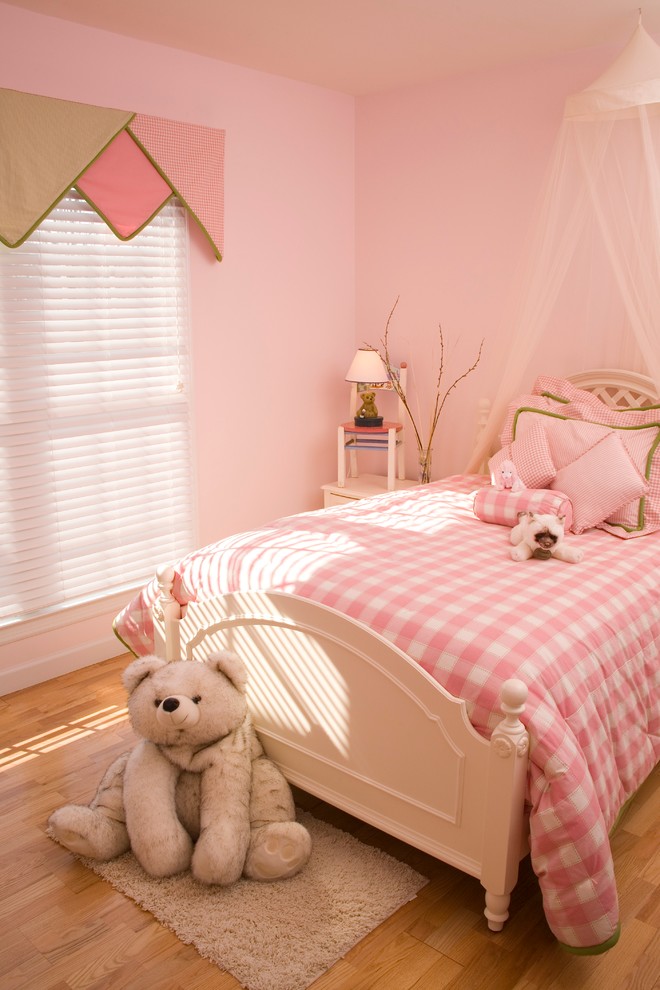 Photo of a mid-sized transitional kids' bedroom for kids 4-10 years old and girls in Nashville with pink walls and light hardwood floors.