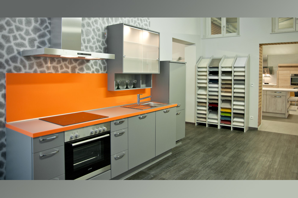 Design ideas for a small contemporary single-wall open plan kitchen in Other with laminate benchtops, stainless steel appliances, no island and orange splashback.